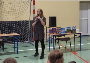 Pani Kasia Kller opowiada dzieciom na sali gimnastycznej o swojej książce.