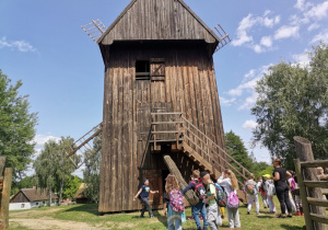 Dzieci podziwiające wiatrak wietrzny w skansenie.