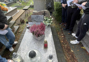 Uczniowie podczas wizyty na cmentarzu, zapalaja symboliczny znicz.