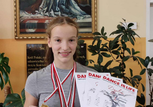 Uczennica prezentuje swoje dyplomy i medale z Ogólnopolskiego Festiwalu Tańca Współczesnego.
