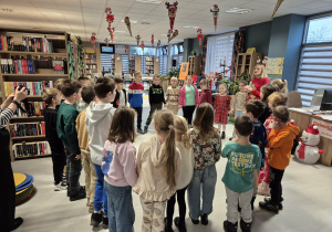 Dzieci zebrane w kole podczas zajęć w bibliotece.
