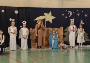 Uczniowie podczas przedstawienia jasełkowego. Na fotografii dzieci odgrywające role Maryi, św. Józefa oraz aiołowie