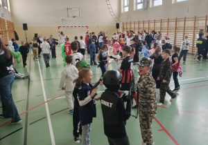 Uczniowie na sali gimnastycznej bawią się podczas balu karnawałowego.