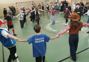 Uczniowie tańczą w kole na sali gimnastycznej