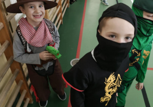 Uczniowie na sali gimnastycznej bawią się podczas balu karnawałowego.