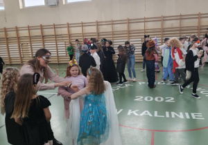 Uczniowie na sali gimnastycznej bawią się podczas balu karnawałowego.