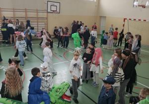 Uczniowie na sali gimnastycznej bawią się podczas balu karnawałowego.