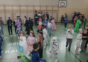 Uczniowie na sali gimnastycznej bawią się podczas balu karnawałowego.