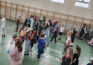 Uczniowie na sali gimnastycznej bawią się podczas balu karnawałowego.