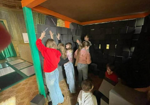 Uczniowie budują mur z piankowych klocków