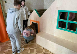 Uczniowie wchodzą do konstrukcji przypominającej dom.