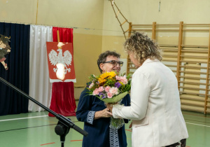 Nauczycielka naszej szkoły odbiera kwiaty z rąk Rady Rodziców