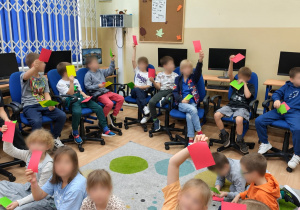 Dzieci z klasy drugiej podczas warsztatów z pedagogiem pokazują kartki, które symbolizują, czy zachowanie jest bezpieczne