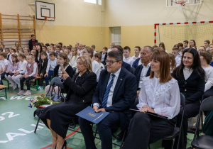 Społeczność szkolna podczas akademii na sali gimnastycznej